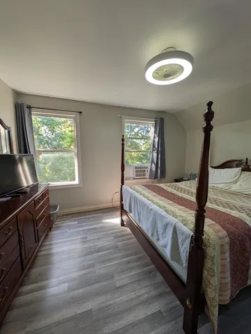a view of a bedroom with wooden floor and windows