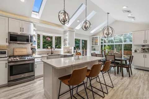 a kitchen with stainless steel appliances granite countertop a stove a sink dishwasher a dining table and chairs with wooden floor