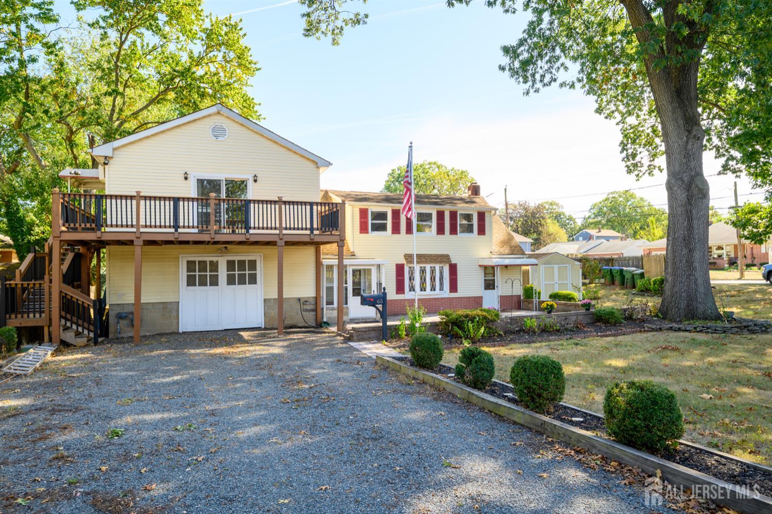65 Orange Street Edison, NJ 08817 - Photo 2 of 51 a view of a white house next to a yard with plants and large trees