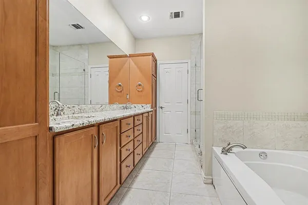 a bathroom with a granite countertop sink a mirror a bathtub and shower