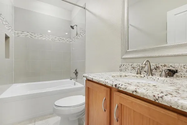 a bathroom with a granite countertop sink a toilet and bathtub