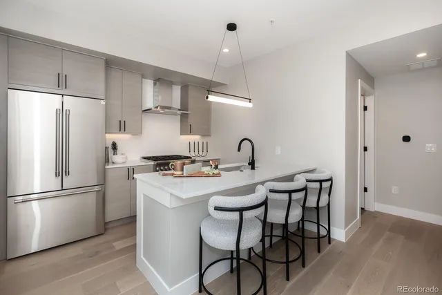 a kitchen with stainless steel appliances a refrigerator a stove a sink and chairs