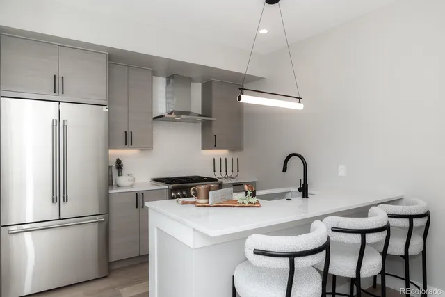 a kitchen with stainless steel appliances a refrigerator a sink a stove a dining table and chairs