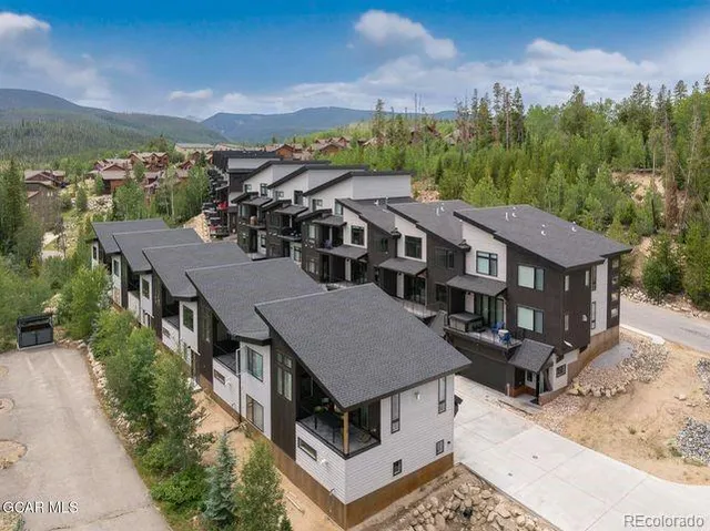 an aerial view of residential houses with yard and mountain view in back