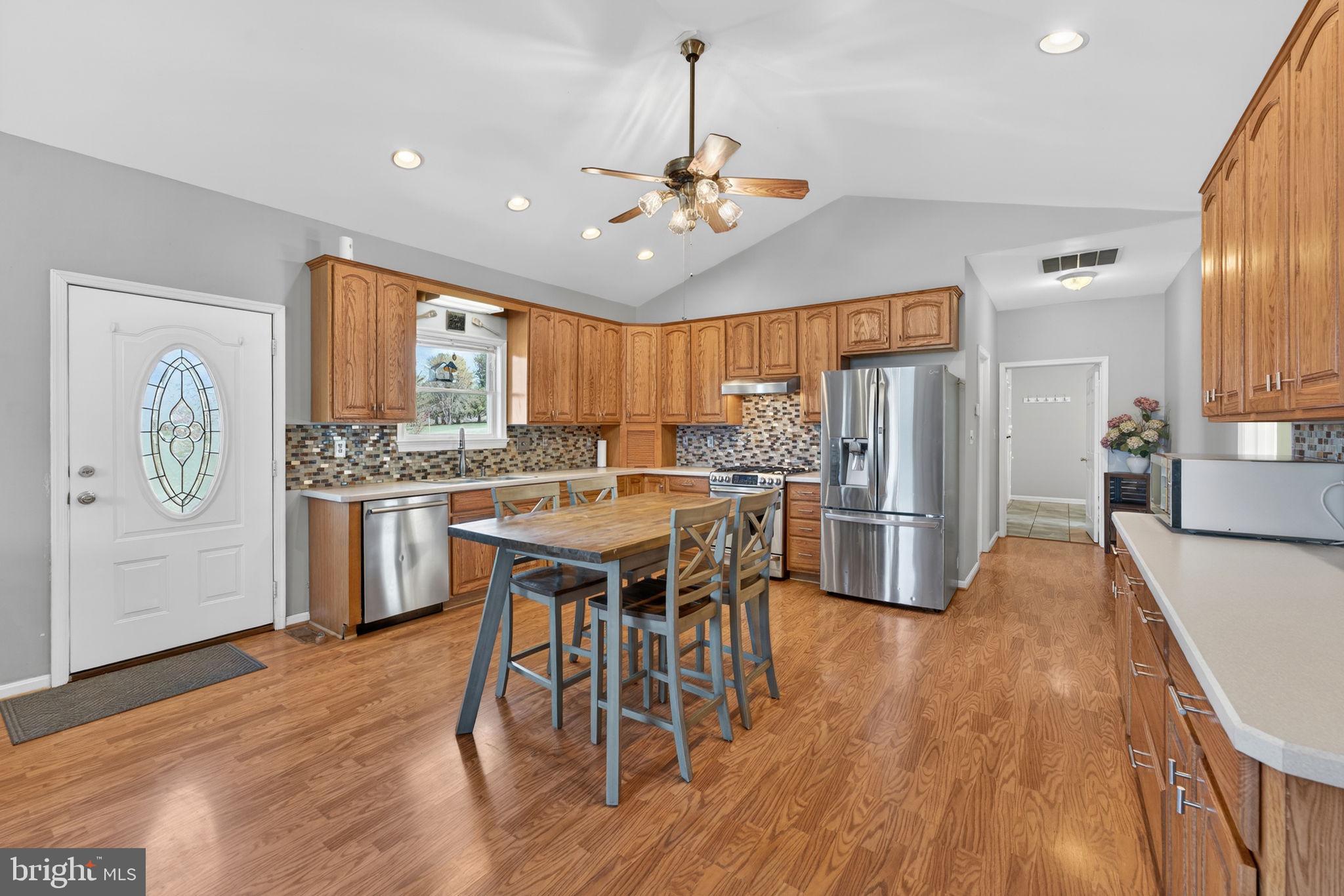 7453 Opal Road Warrenton, VA 20186 - Photo 8 of 53 a kitchen with stainless steel appliances kitchen island granite countertop a table chairs refrigerator and microwave