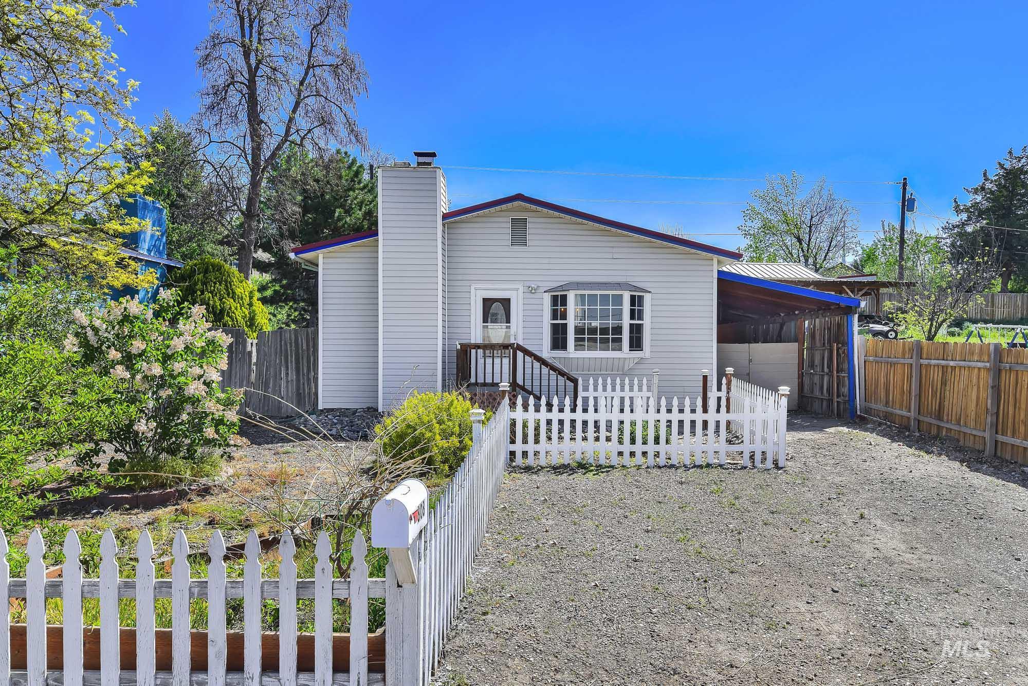 Property exterior featuring light gray siding, a prominent bay window, and a white picket fence