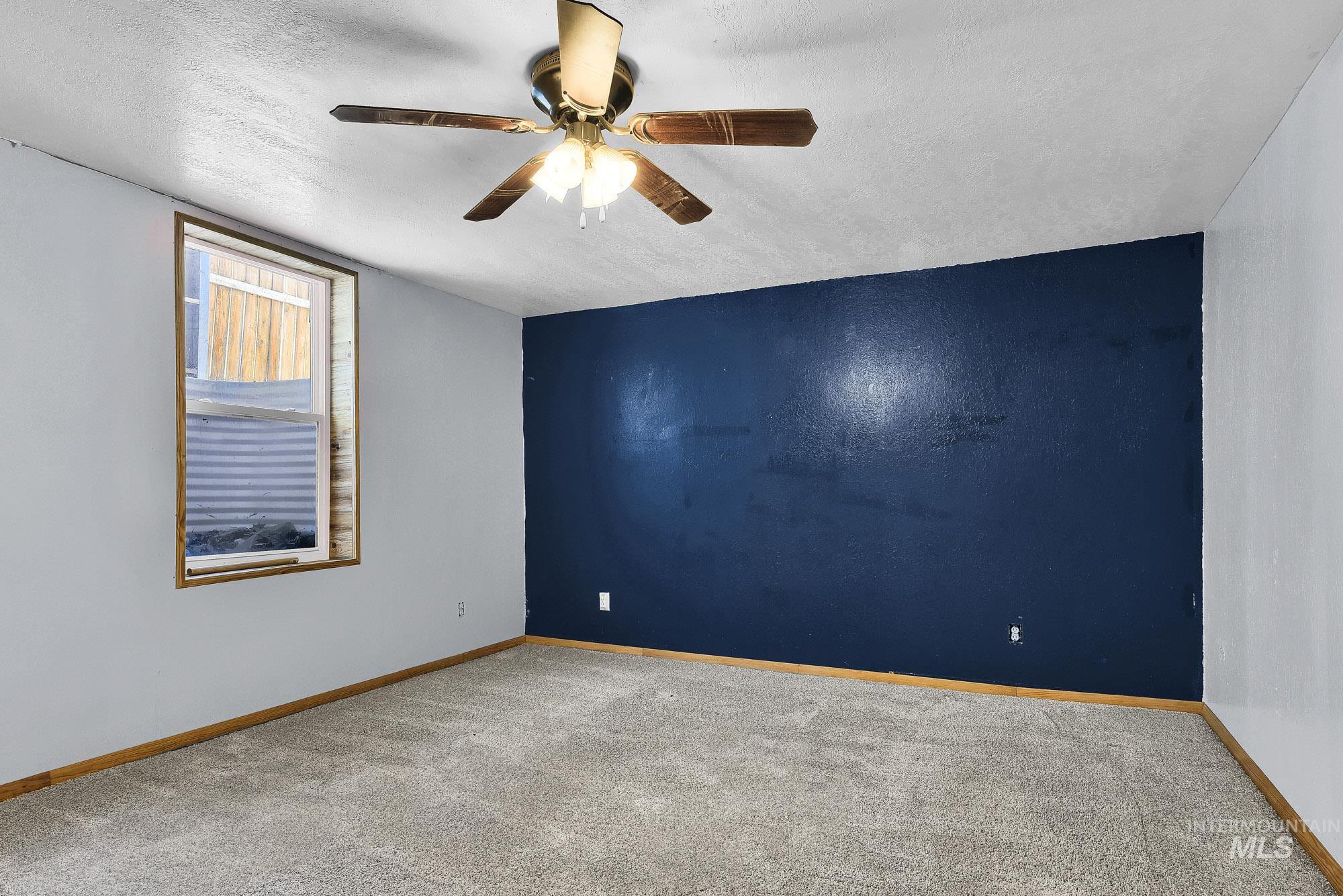808 North A Street Parma, ID 83660 - Photo 18 of 29 Carpeted interior space featuring a single window, a ceiling fan with integrated lighting, a dark accent wall, and light-colored baseboards