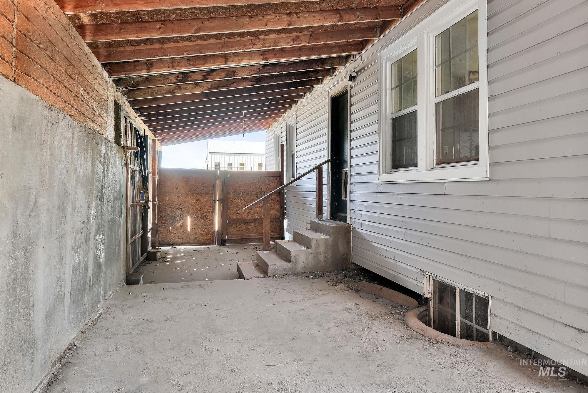 808 North A Street Parma, ID 83660 - Photo 25 of 29 Covered outdoor space featuring a concrete floor, exposed wood ceiling beams, and a concrete retaining wall