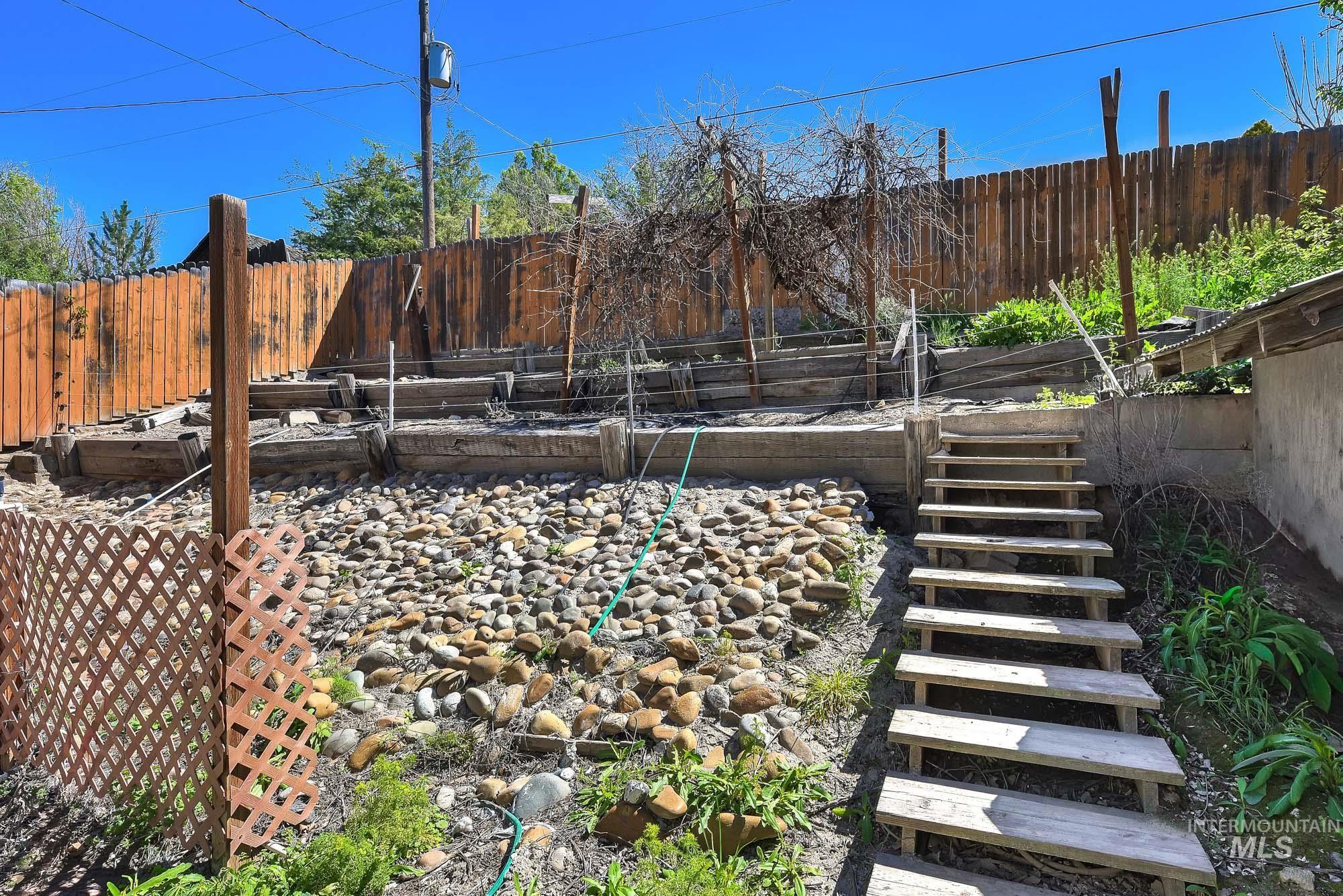 808 North A Street Parma, ID 83660 - Photo 27 of 29 Terraced backyard featuring a rock bed, wood retaining walls, and a wood privacy fence
