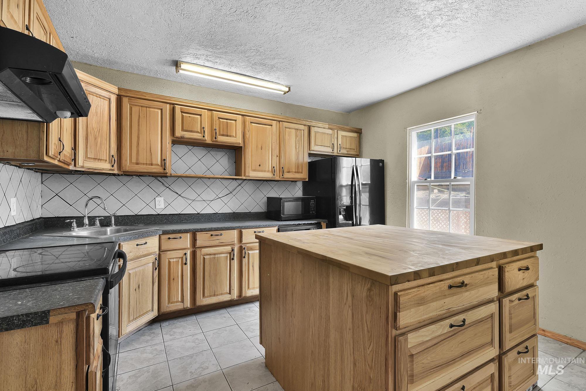 808 North A Street Parma, ID 83660 - Photo 6 of 29 Kitchen featuring wood cabinetry, dark countertops, and a full tile backsplash