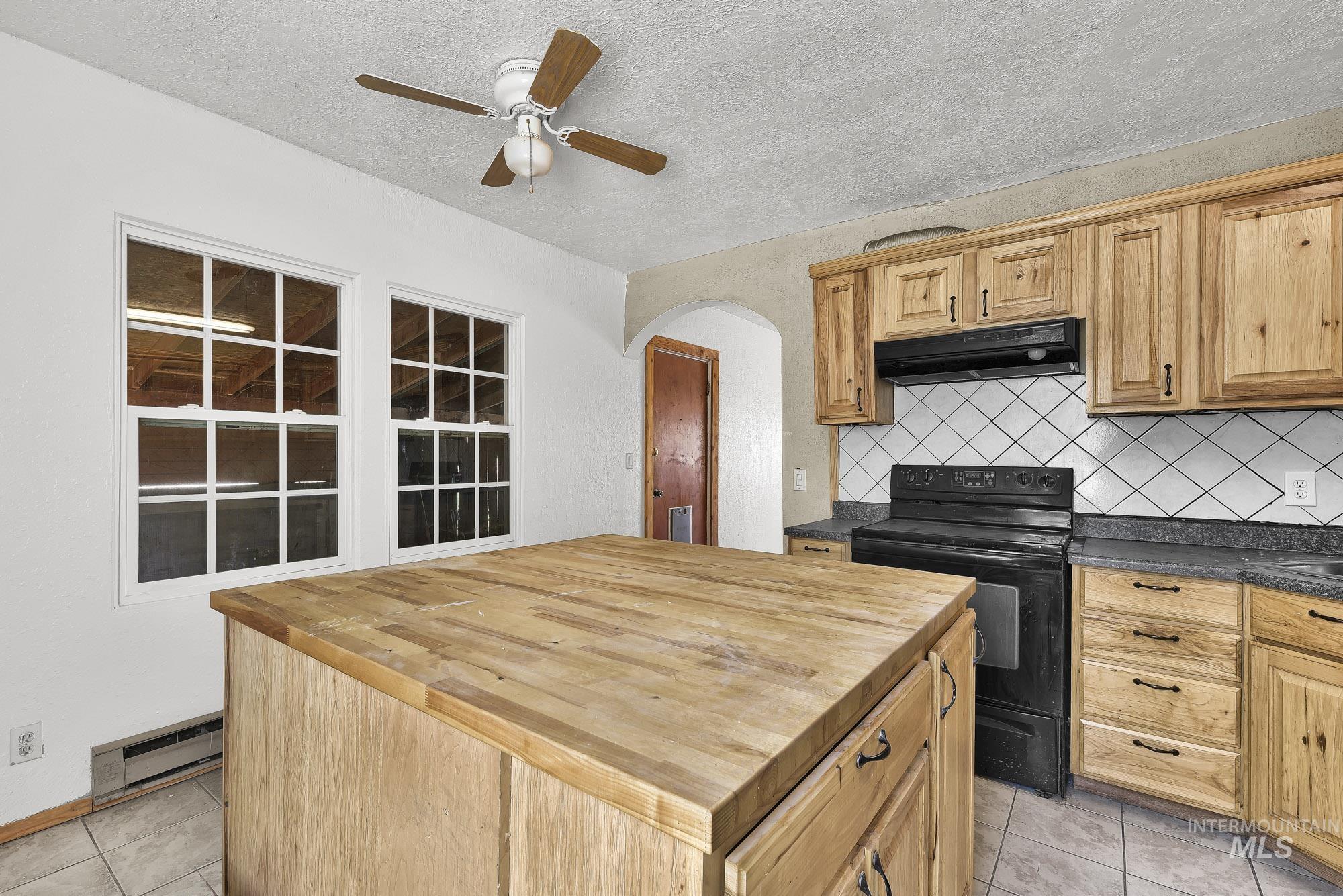 808 North A Street Parma, ID 83660 - Photo 10 of 29 Kitchen featuring a butcher block island, wood-finish cabinetry, tile flooring, a built-in range, and a ceiling fan