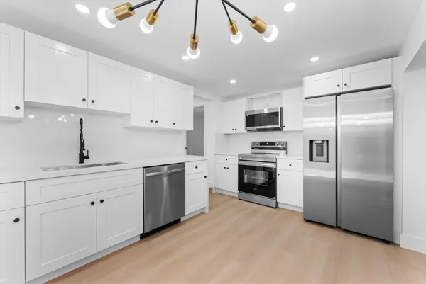 a kitchen with cabinets stainless steel appliances and wooden floor