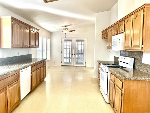a large kitchen with stainless steel appliances granite countertop a stove a sink and a granite counter tops with white cabinets