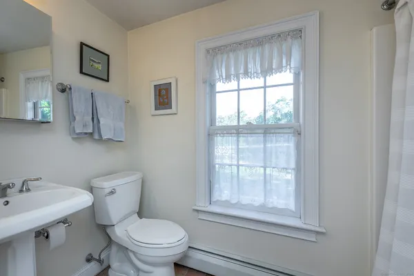 a bathroom with a toilet a sink a window and mirror