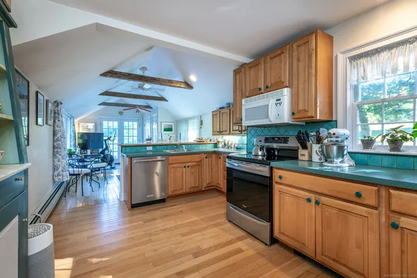 a kitchen with stainless steel appliances granite countertop wooden floors a stove a sink and white cabinets