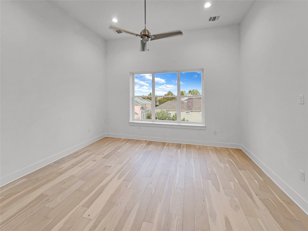 3807 Threadgill Street Austin, TX 78723 - Photo 13 of 36 an empty room with wooden floor ceiling fan and windows