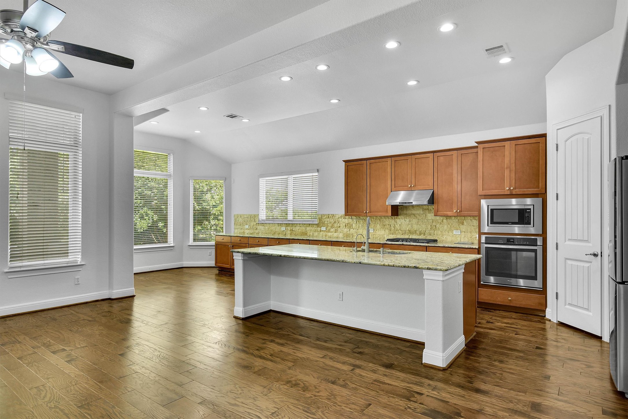 2325 Blended Tree Ranch Drive Leander, TX 78641 - Photo 11 of 35 A well-lit kitchen with rich hardwood flooring and a functional island, ready for culinary endeavors.
