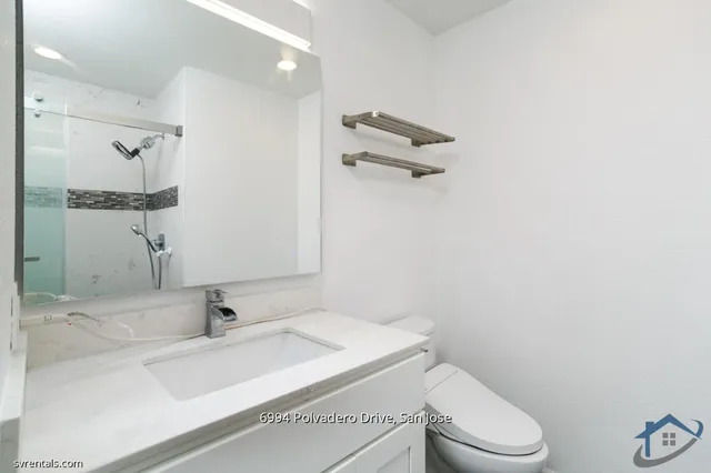 a bathroom with a granite countertop sink a toilet and a mirror