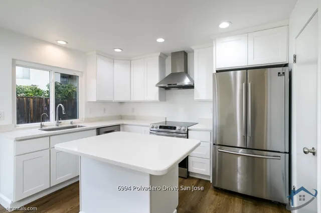 a kitchen with stainless steel appliances a refrigerator a sink a stove a microwave and island