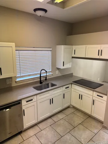 a white kitchen with sink and cabinets