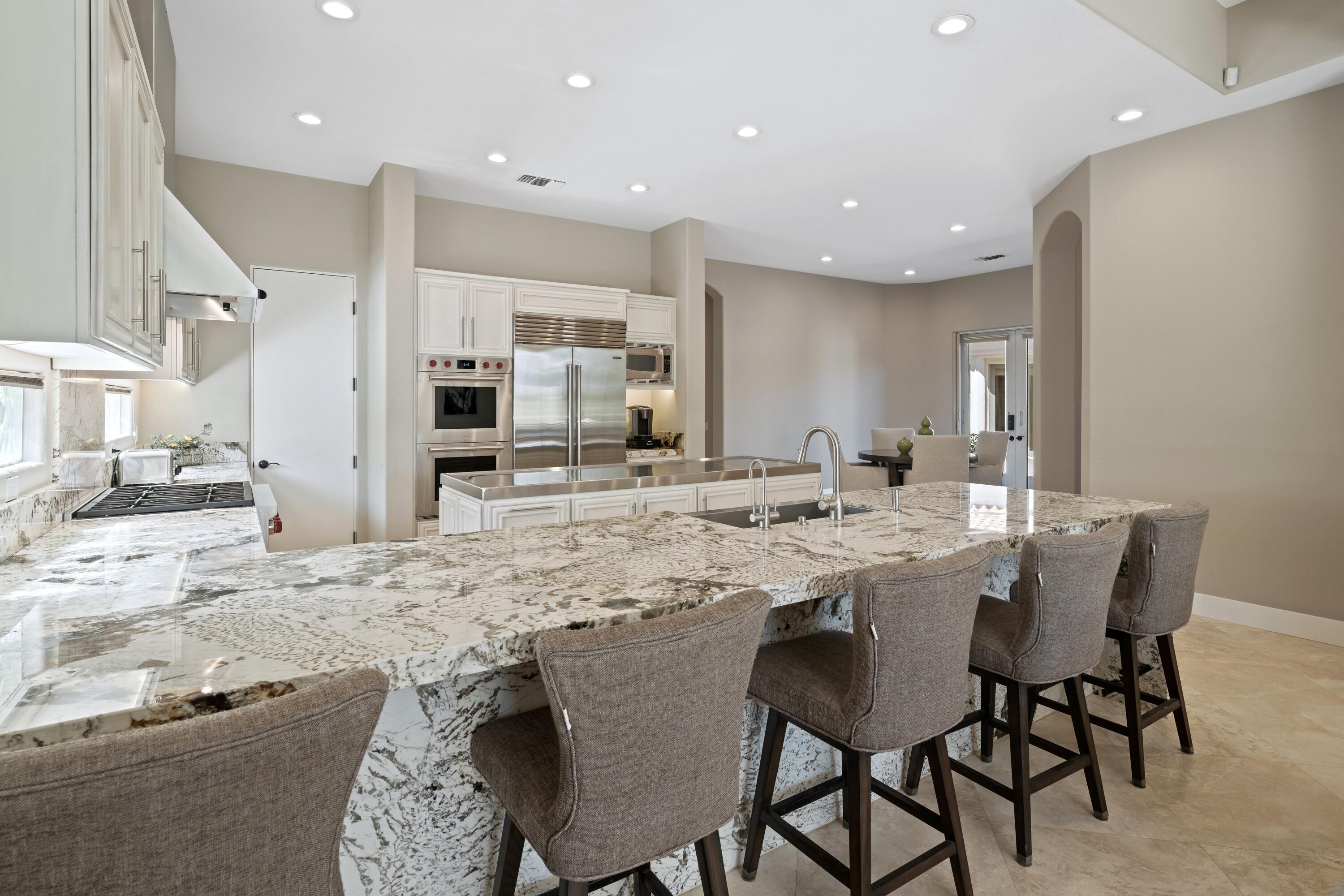 306 Loch Lomond Road Rancho Mirage, CA 92270 - Photo 16 of 60 a kitchen with stainless steel appliances granite countertop a table chairs sink and cabinets