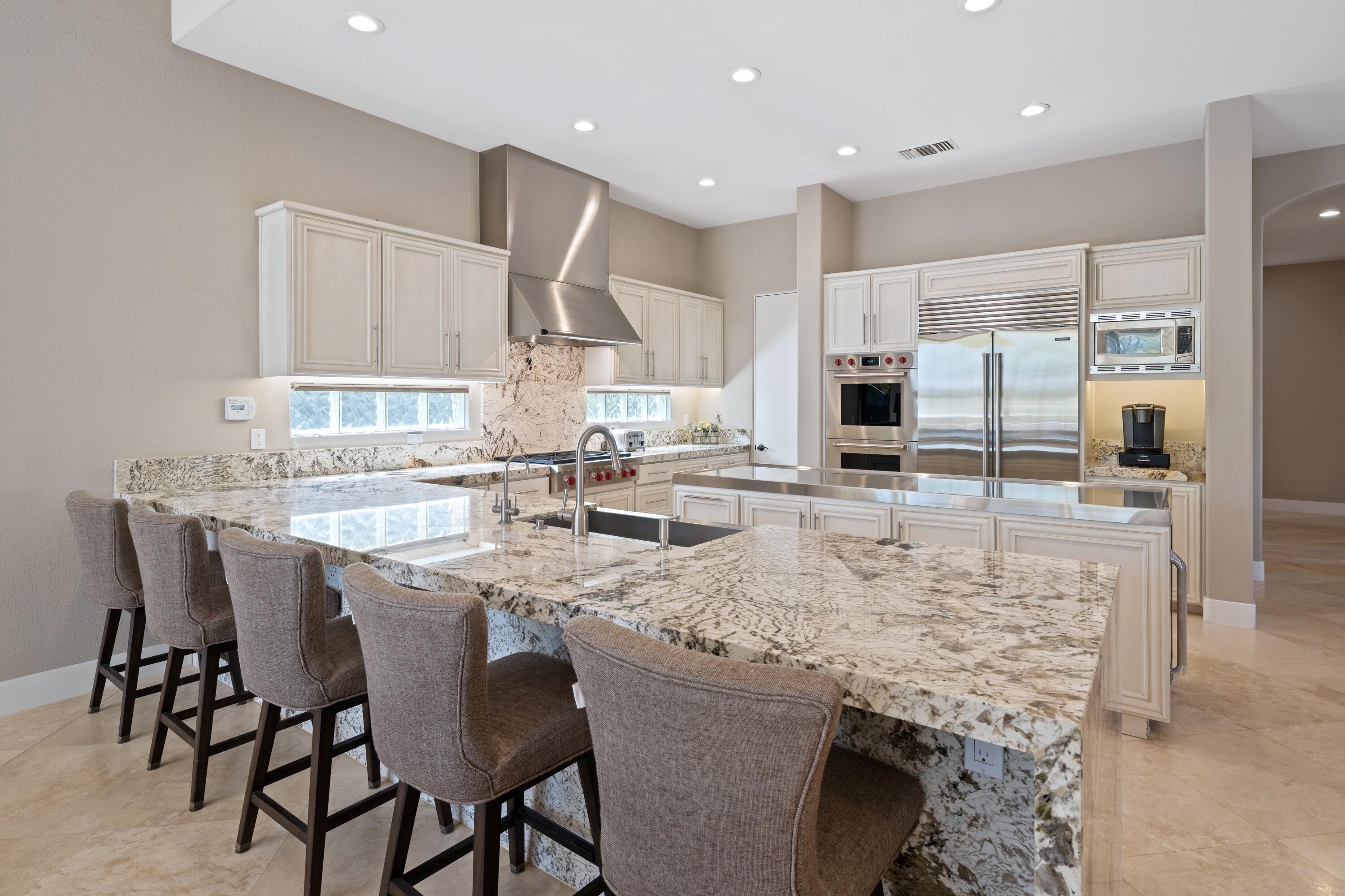 306 Loch Lomond Road Rancho Mirage, CA 92270 - Photo 17 of 60 a kitchen with kitchen island granite countertop a table chairs sink and cabinets