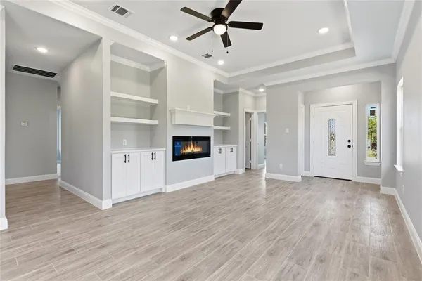 an empty room with wooden floor fireplace and windows