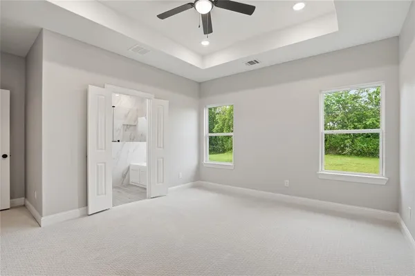 an empty room with windows and a chandelier fan