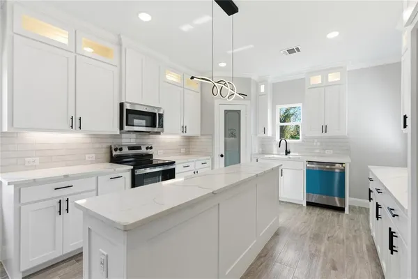 a kitchen with a sink a counter top space stainless steel appliances and cabinets