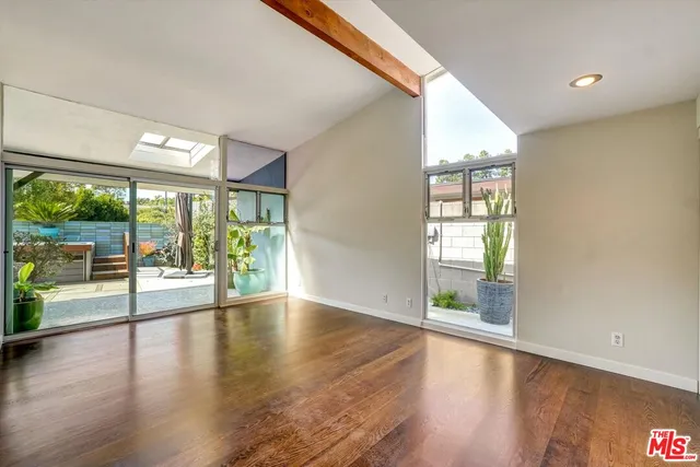 a view of a patio with table and chairs potted plants and floor to ceiling window