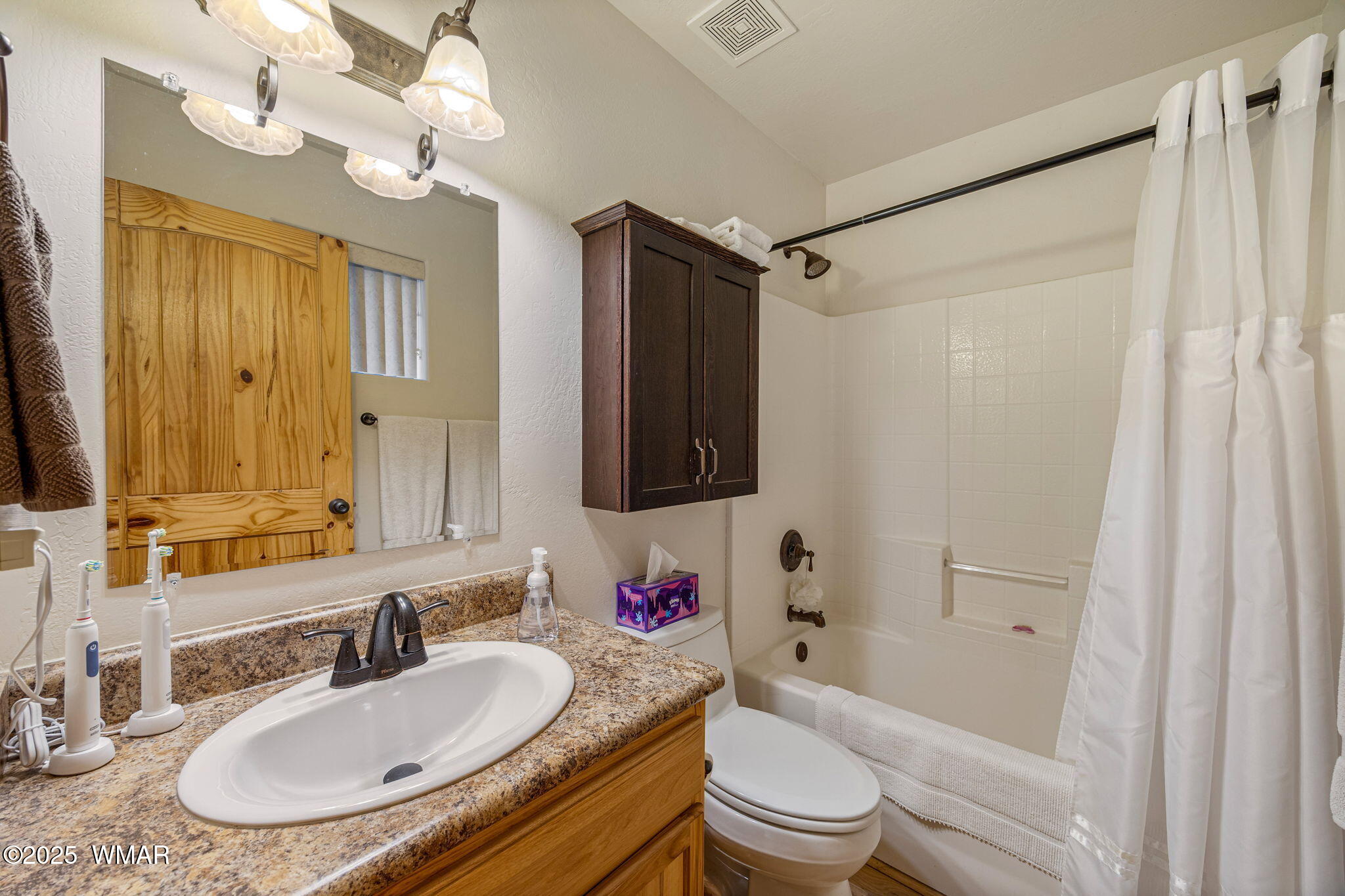 3142 Ranch Road Overgaard, AZ 85933 - Photo 17 of 35 a bathroom with a granite countertop sink a toilet a mirror a bathtub and shower