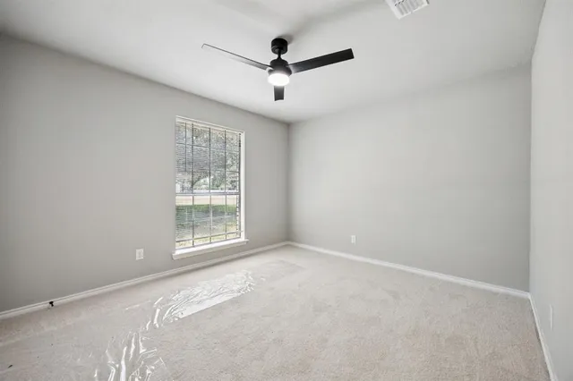 an empty room with ceiling fan and windows