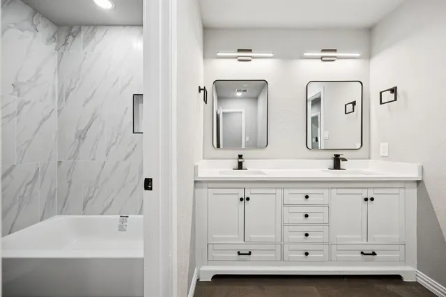 a bathroom with a double vanity sink mirror and bathtub