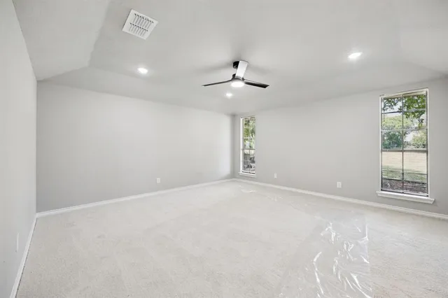 an empty room with a ceiling fan and windows
