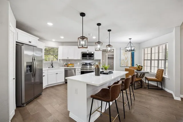 a kitchen with stainless steel appliances kitchen island granite countertop a table chairs stove and refrigerator