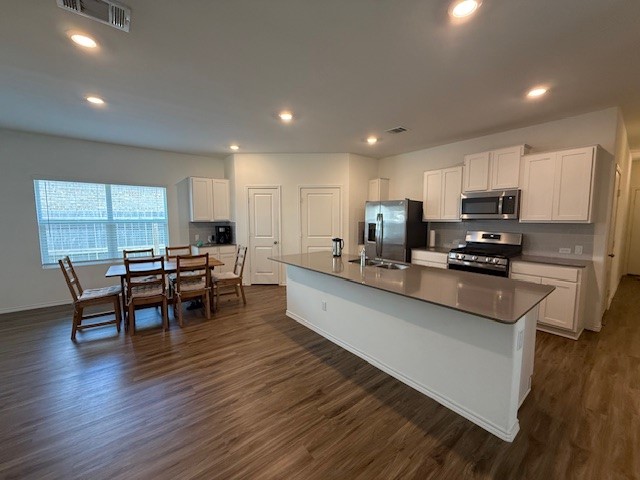 1745 Woolsey Way Leander, TX 78641 - Photo 8 of 20 a kitchen with stainless steel appliances kitchen island granite countertop a stove a sink a dining table and chairs