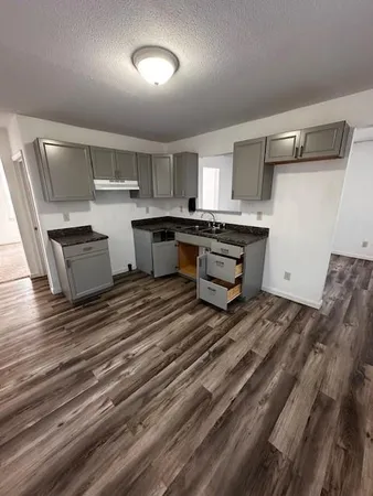 a room with kitchen island white cabinets and wooden floor