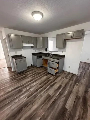 a room with kitchen island white cabinets and wooden floor
