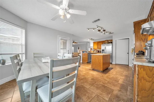 a view of a kitchen and kitchen with furniture a ceiling fan and window