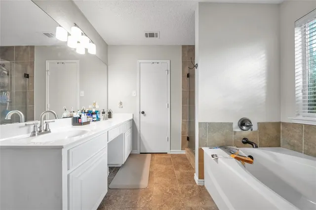 a bathroom with a tub a sink a mirror and a shower