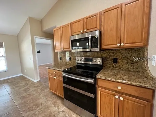 a kitchen with stainless steel appliances granite countertop a stove a microwave and a sink