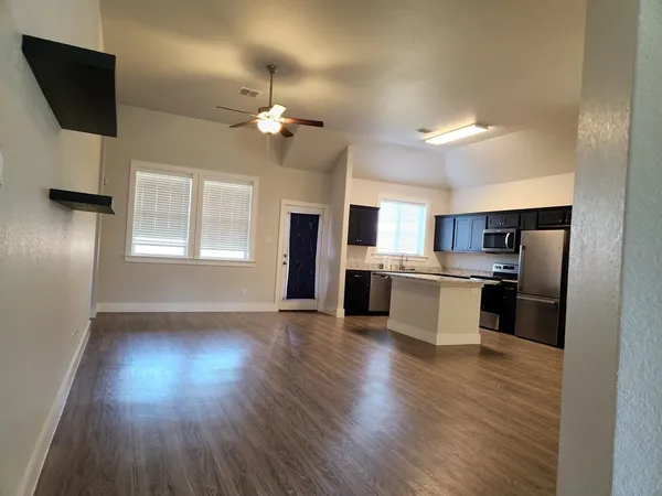 a kitchen with stainless steel appliances a refrigerator a stove a sink dishwasher and a microwave with wooden floor