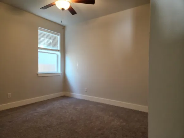 an empty room with a window and a fan