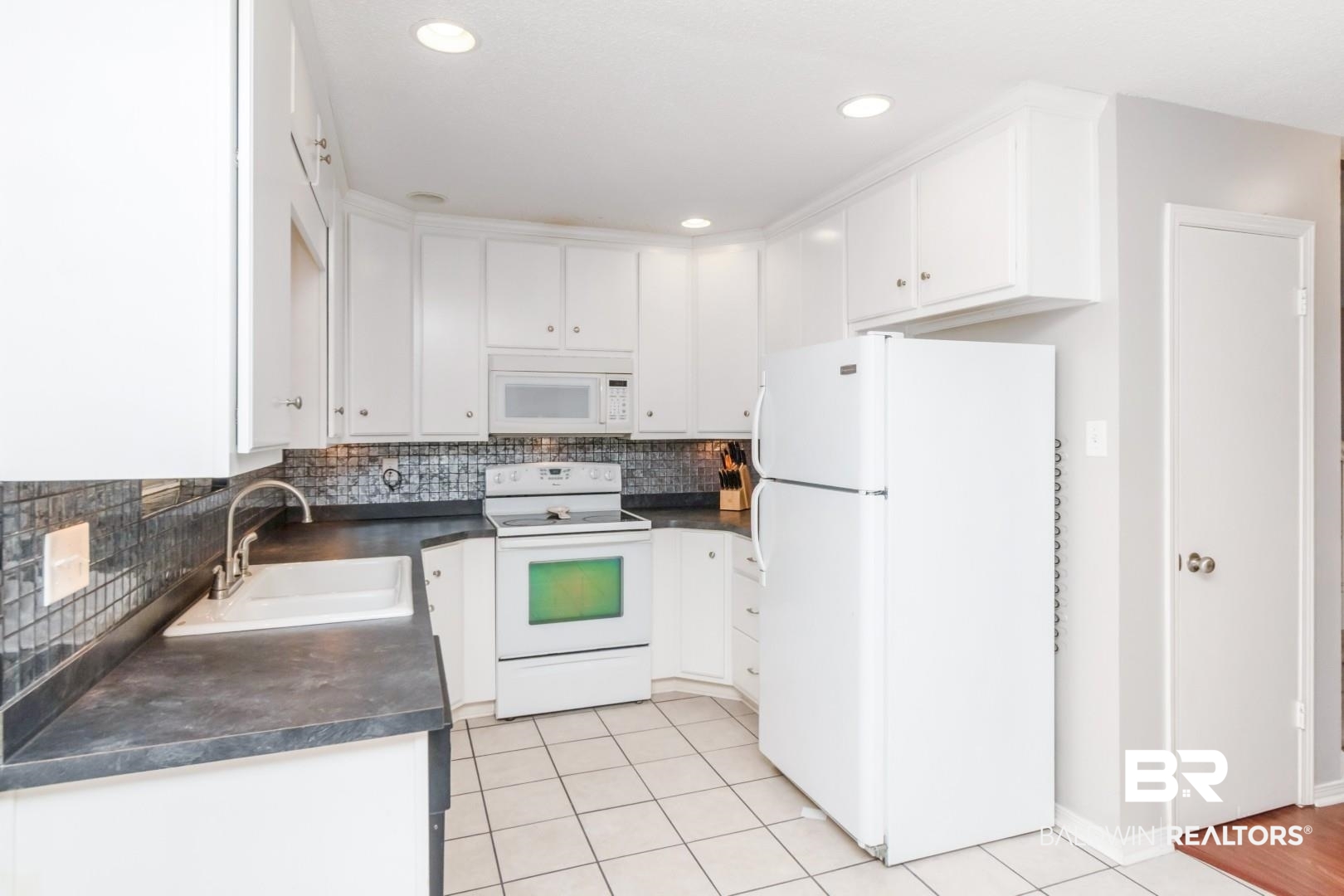118 Du Rhu Drive, Unit H Mobile, AL 36608 - Photo 6 of 19 Kitchen featuring white cabinetry, dark countertops, a mosaic tile backsplash, recessed lighting, and white tile flooring