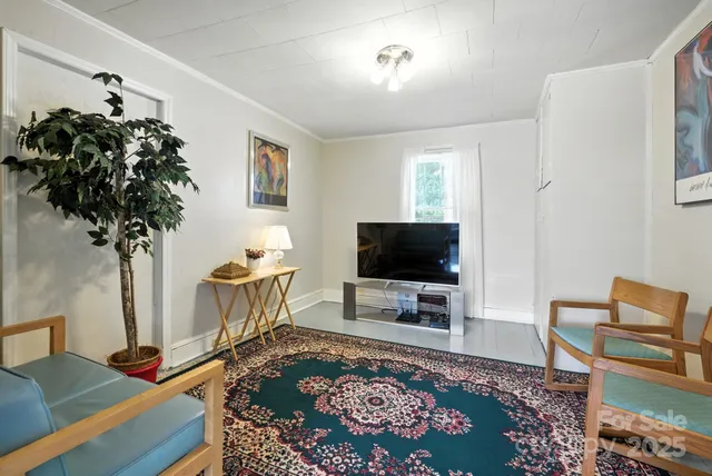 a living room with painting on the wall and a potted plant