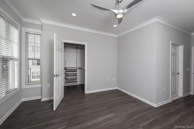 an empty room with wooden floor ceiling fan and windows