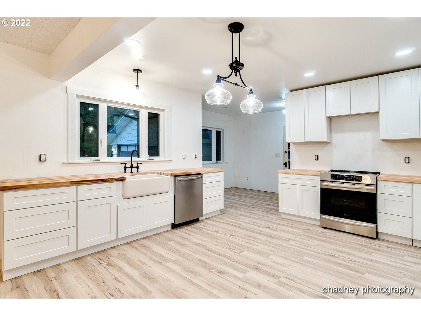 606 Southeast Northway Road Corbett, OR 97019 - Photo 11 of 32 a large white kitchen with kitchen island a sink dishwasher a stove a dining table and chairs with wooden floor