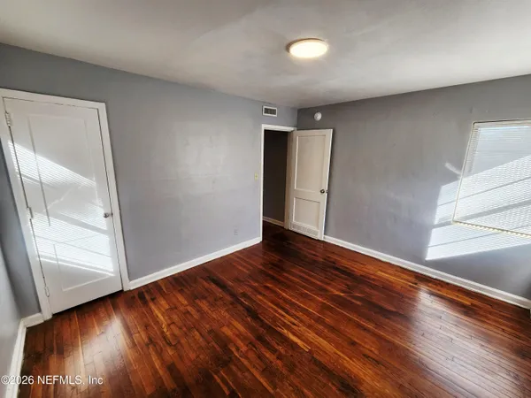 a view of an empty room with wooden floor and a window