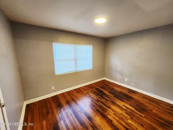 a view of empty room with wooden floor