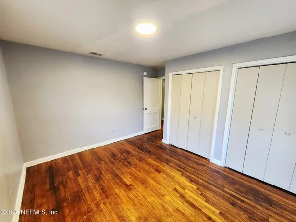 a view of empty room with wooden floor